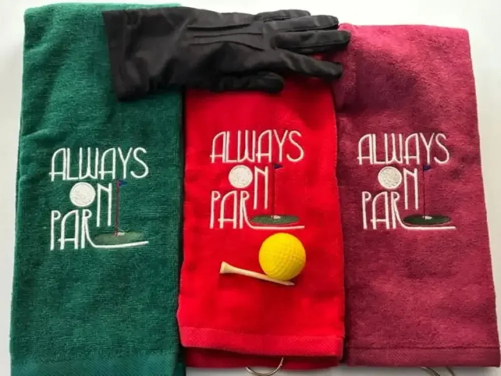 Tri-fold golf towels with 'Always On Par' embroidery, glove, yellow golf ball and tee