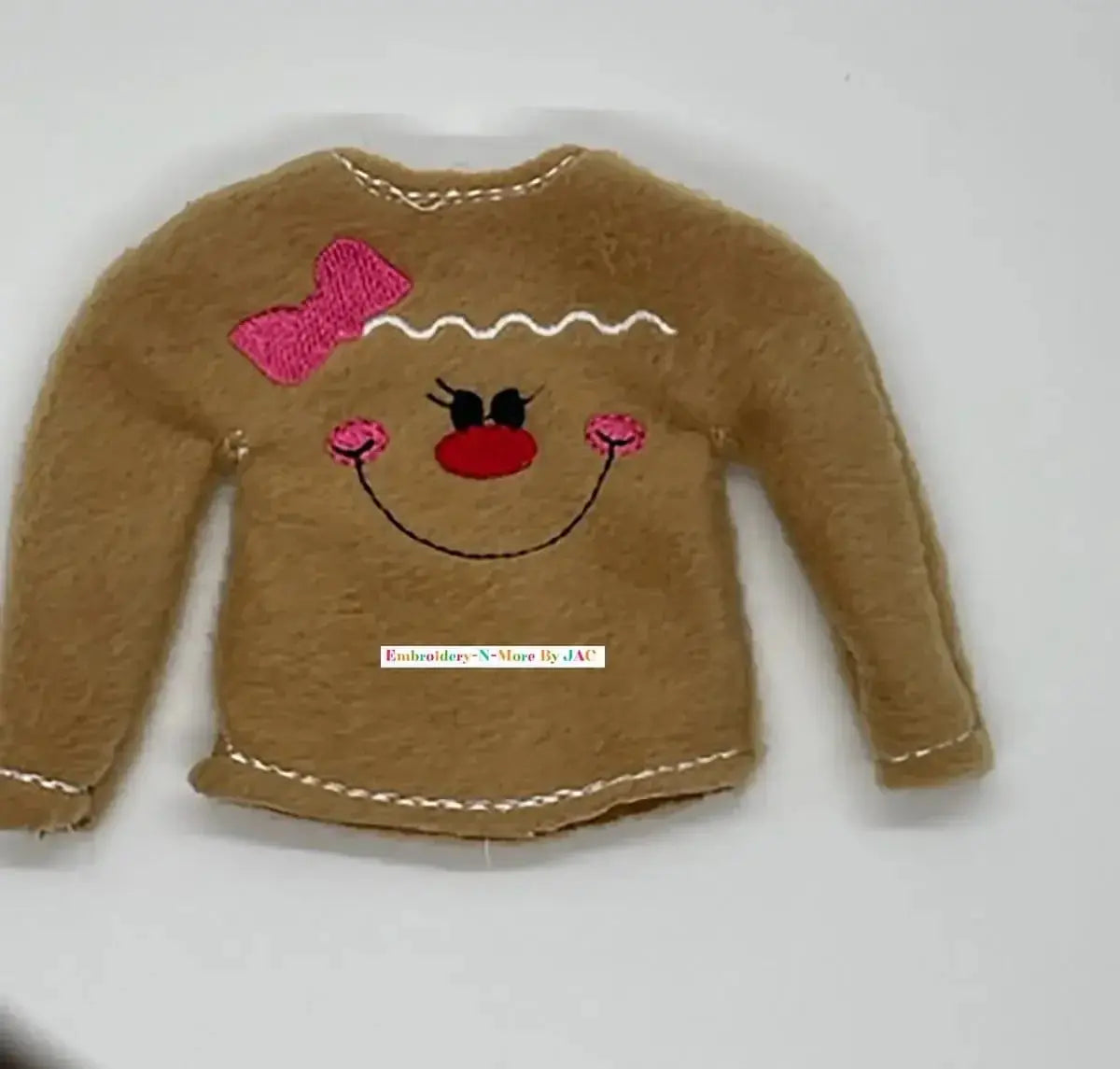 Brown felt doll sweater with embroidered gingerbread face, pink bow, and decorative stitching