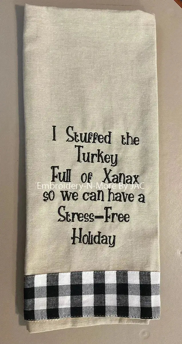 Funny holiday kitchen towel with embroidered joke text and black plaid trim