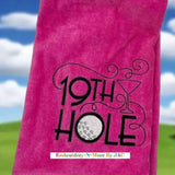 Pink tri-fold golf towel with embroidered 19th Hole design, golf ball, and martini glass.