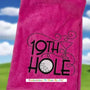 Pink tri-fold golf towel with embroidered 19th Hole design, golf ball, and martini glass.