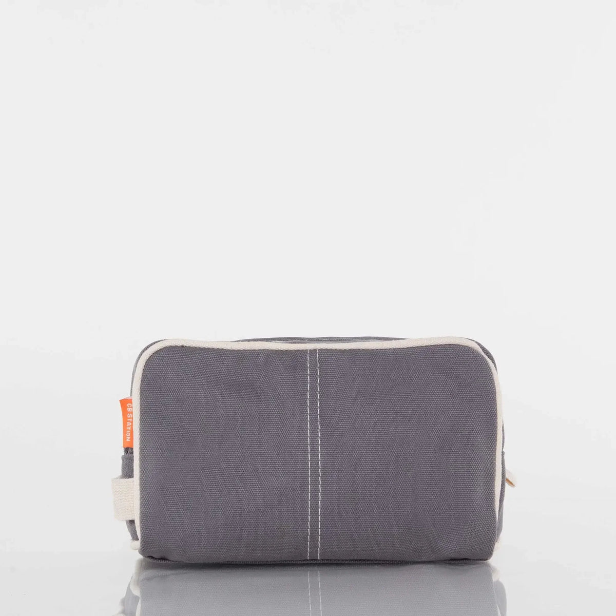Gray canvas toiletry bag with white trim and orange side tag on white background