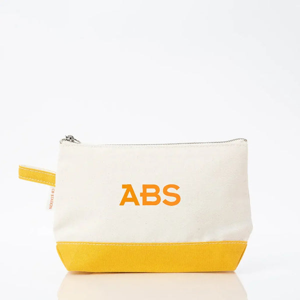 Personalized canvas makeup bag with yellow base and ABS monogram in orange lettering