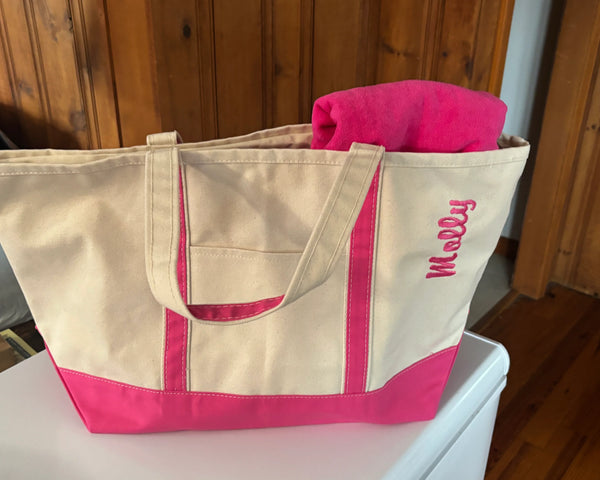 Personalized canvas tote bag with pink accents and name embroidery, holding a pink towel