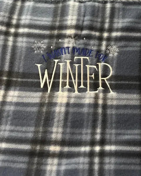 Plaid fleece blanket with embroidered I wasn't made for winter and snowflake design