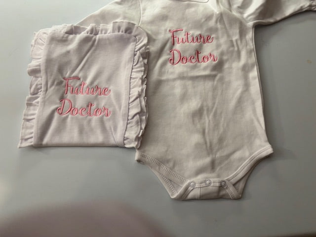 White baby bodysuit and ruffled blanket with pink 'Future Doctor' embroidery