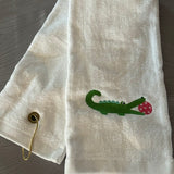 white trifold towel embroidered with a green alligator with a hot pink pickball in it's mouth