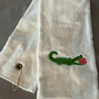 white trifold towel embroidered with a green alligator with a hot pink pickball in it's mouth