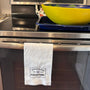 Linen hemsttiched kitchen towel embroidered with Entering Edgartown town sign hanging on a oven handle