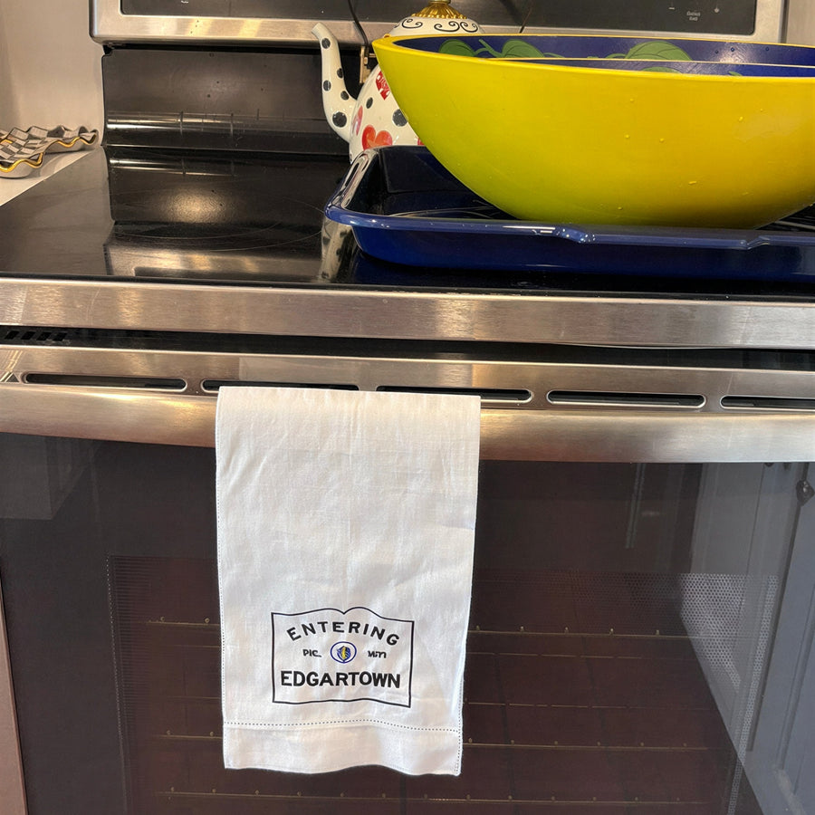 Linen hemsttiched kitchen towel embroidered with Entering Edgartown town sign hanging on a oven handle