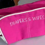 Pink embroidered diapers and wipes pouch for baby essentials on white surface