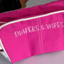Pink embroidered diapers and wipes pouch for baby essentials on white surface