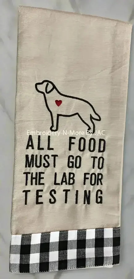Embroidered kitchen towel with dog outline, heart detail, buffalo plaid border, and food testing quote