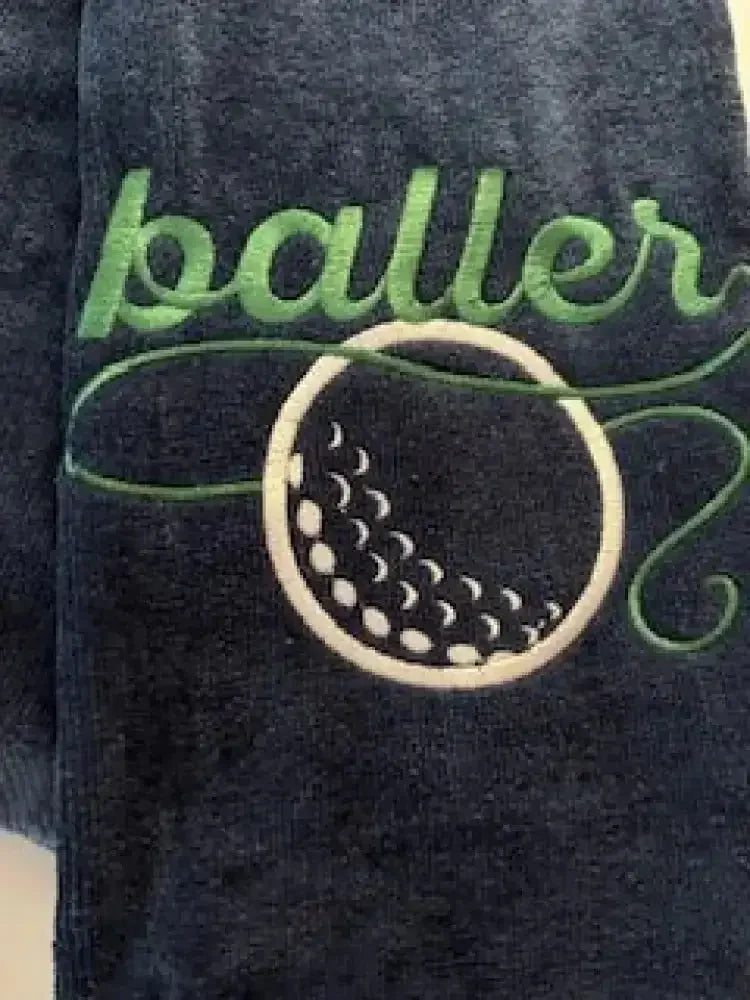 Navy blue golf towel with green baller text and embroidered golf ball design
