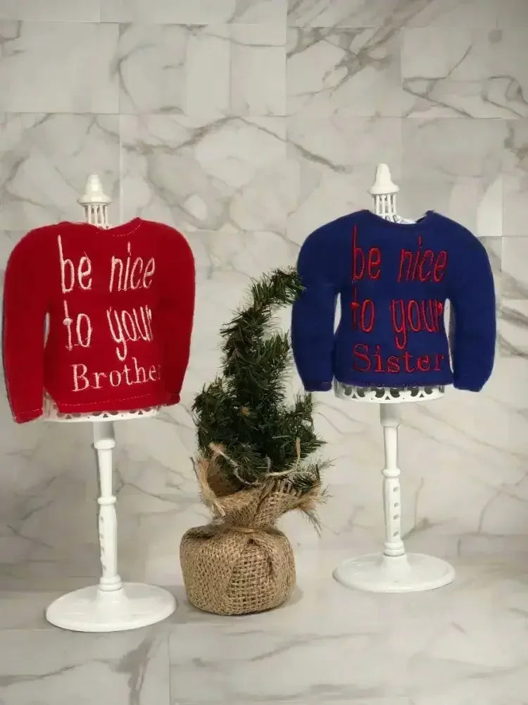 Red and blue embroidered elf sweaters on stands with be nice to your brother and sister text