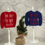 Red and blue embroidered elf sweaters on stands with be nice to your brother and sister text