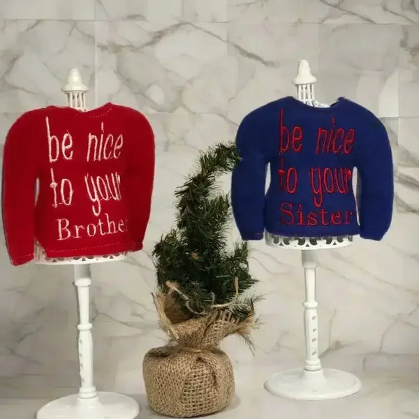 Red and blue embroidered elf sweaters on stands with be nice to your brother and sister text