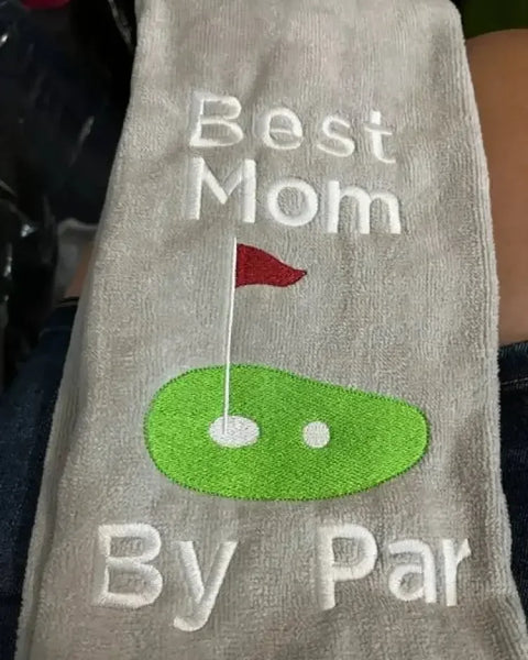 Embroidered golf towel with text 'Best Mom By Par' and green golf green with flag design
