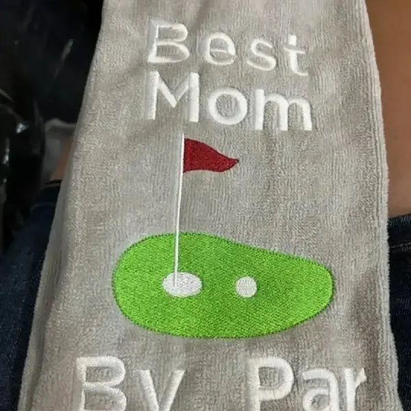 Embroidered golf towel with text 'Best Mom By Par' and green golf green with flag design
