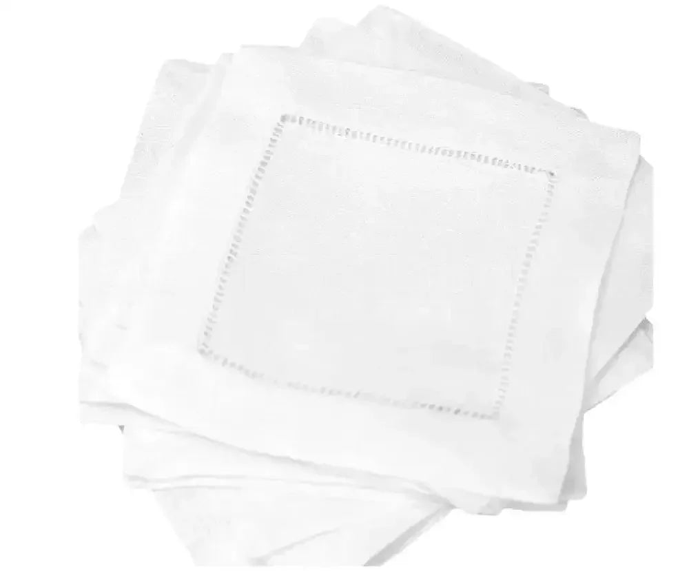 Set of white linen cocktail napkins with hemstitch border, stacked on white background