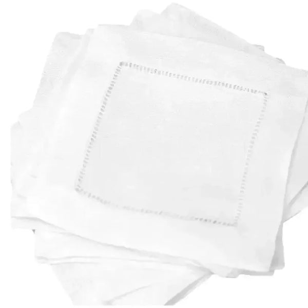 Set of white linen cocktail napkins with hemstitch border, stacked on white background