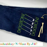 Navy tri-fold golf towel with embroidered green 'Decisions' text, golf clubs, and tees