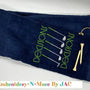 Navy tri-fold golf towel with embroidered green 'Decisions' text, golf clubs, and tees