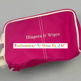 Pink diaper and wipes case bag with embroidered text, zip closure, and white trim.