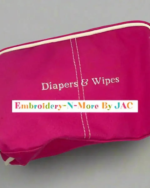 Pink diaper and wipes case bag with embroidered text, zip closure, and white trim.