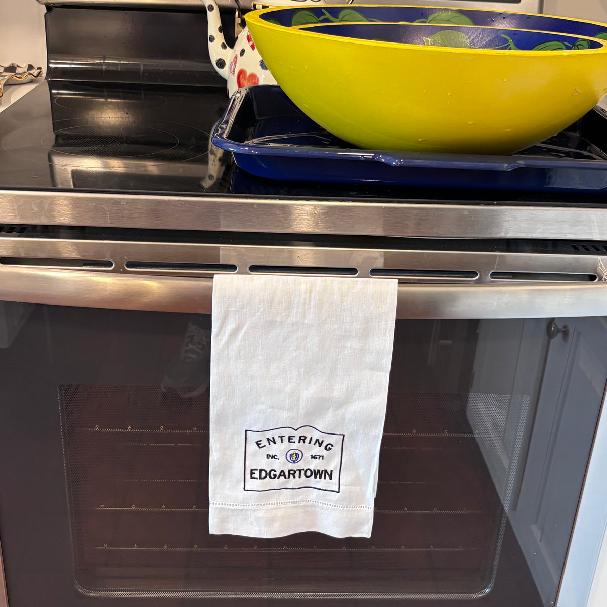 Linen hemsttiched kitchen towel embroidered with Entering Edgartown town sign hanging on a oven handle