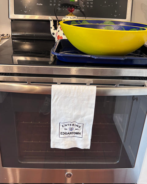 Linen hemsttiched kitchen towel embroidered with Entering Edgartown town sign hanging on a oven handle