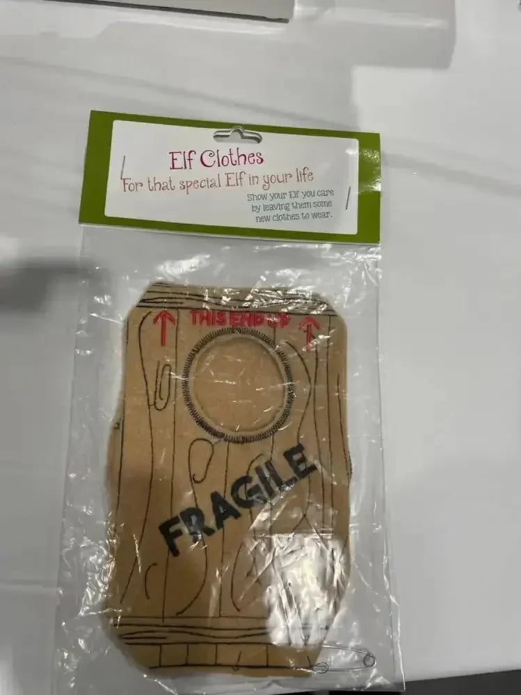 Elf costume with wood print and 'FRAGILE' text, packaged for holiday gifting.
