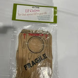Elf costume with wood print and 'FRAGILE' text, packaged for holiday gifting.