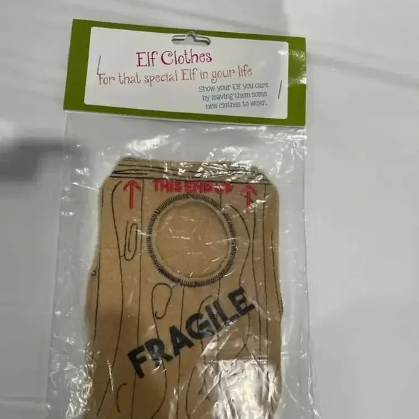 Elf costume with wood print and 'FRAGILE' text, packaged for holiday gifting.
