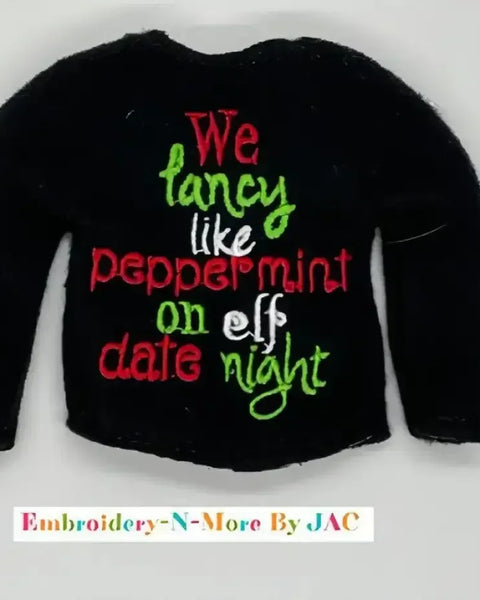 Black sweater with embroidered festive text in red, green, and white, holiday themed.