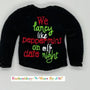 Black sweater with embroidered festive text in red, green, and white, holiday themed.