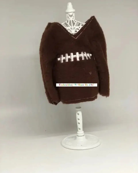 Brown elf sweater styled like a football with white embroidered stitching on display stand