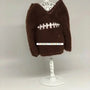 Brown elf sweater styled like a football with white embroidered stitching on display stand