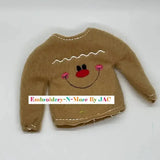 Brown embroidered gingerbread boy sweater with smiling face and pink cheeks, holiday accessory