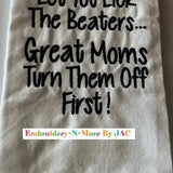 White flour sack kitchen towel with humorous embroidered text and black plaid border.