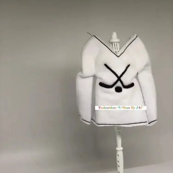 White hockey-themed elf sweater with crossed hockey sticks, displayed on a mannequin stand.