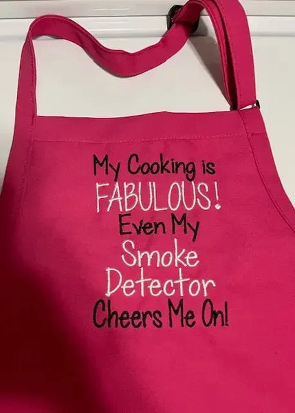 Hot pink apron with humorous white and black embroidered cooking quote on the front