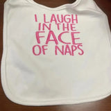 White baby bib with pink embroidered text saying 'I laugh in the face of naps'
