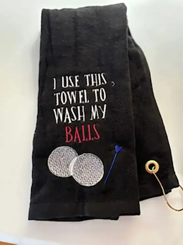 Black personalized golf towel with embroidered golf balls, tee, and humorous text.