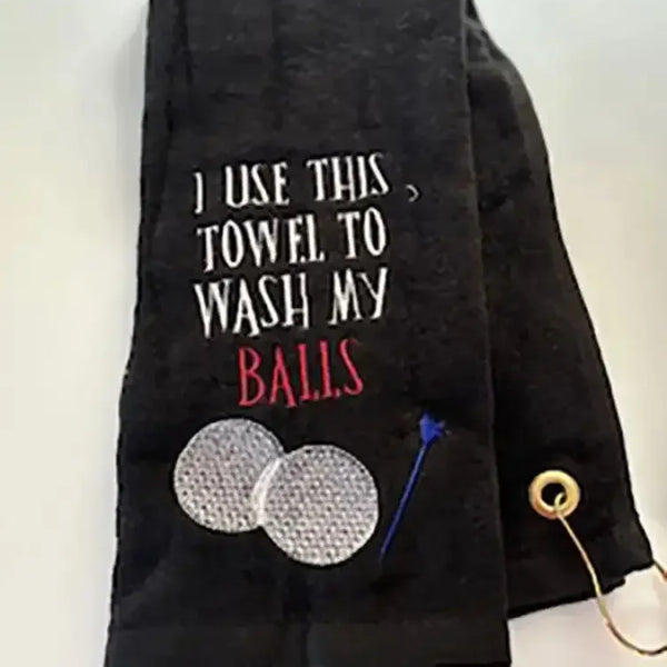 Black personalized golf towel with embroidered golf balls, tee, and humorous text.
