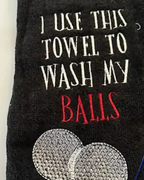 Black embroidered golf towel with text and two white golf balls design