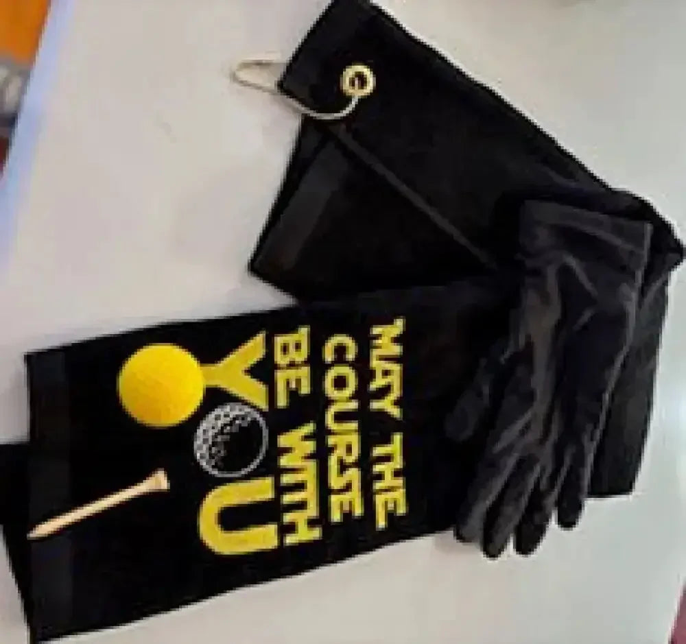 Black embroidered golf towel with yellow golf ball and tee, and 'May the Course Be With You' text