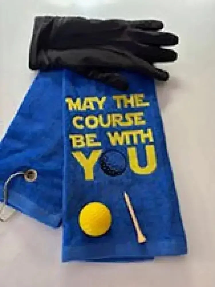 Blue embroidered golf towel with 'May the course be with you' text, golf glove, ball, and tee