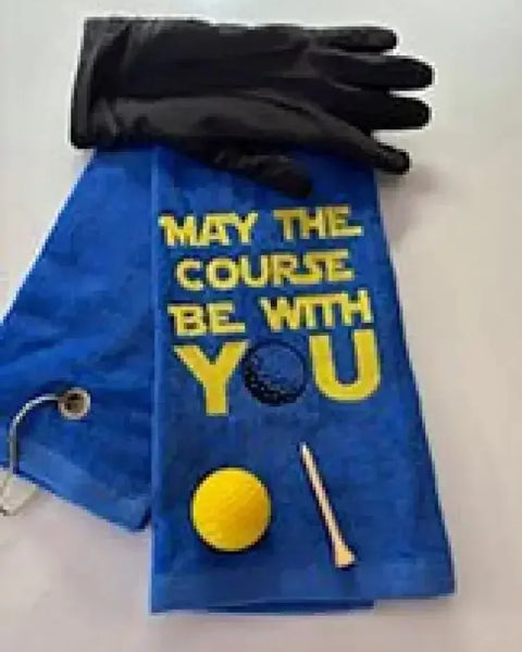 Blue embroidered golf towel with 'May the course be with you' text, golf glove, ball, and tee