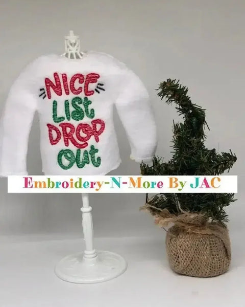White elf sweater with 'Nice List Drop Out' embroidered in red and green, next to mini Christmas tree.